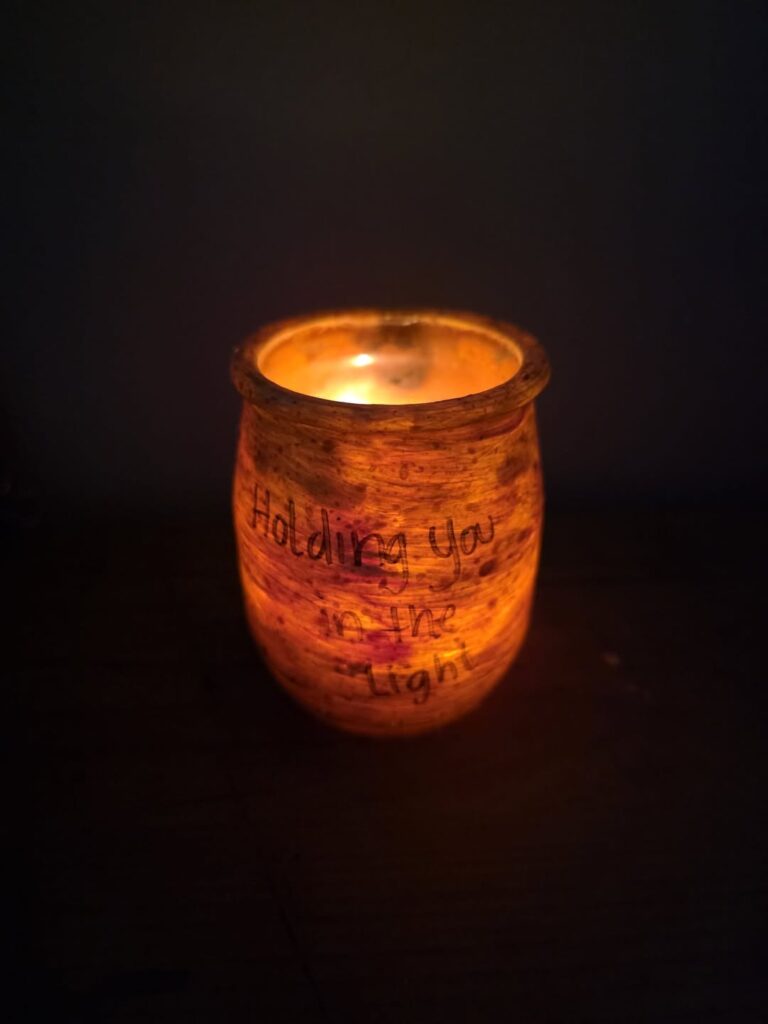 Candle in a jar marked holding you in our hearts